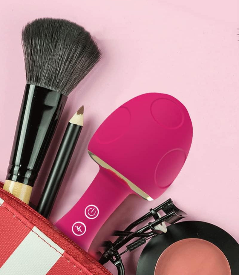 Makeup tools including a brush, pencil, pink tool, and red pouch on a pink background