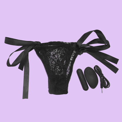 Black lace thong with satin bows and remote control on a white background