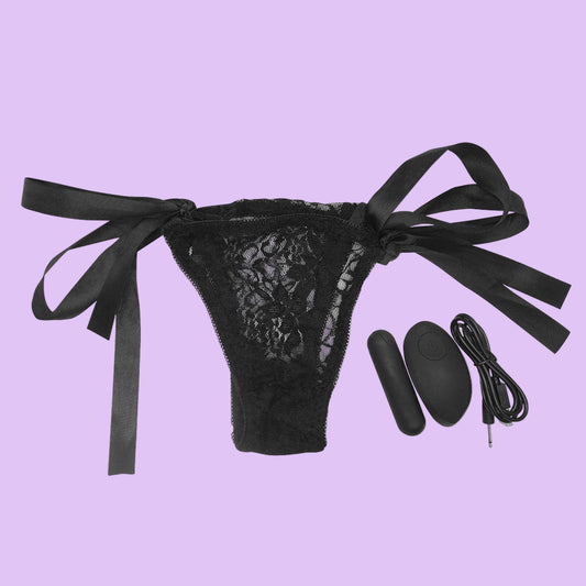 Black lace thong with satin bows and remote control on a white background